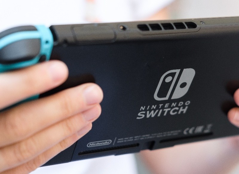Person hält eine Nintendo Switch in der Hand.