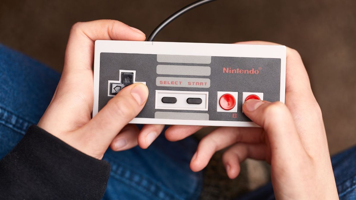 Person hÃ¤lt einen NES-Controller in der Hand.