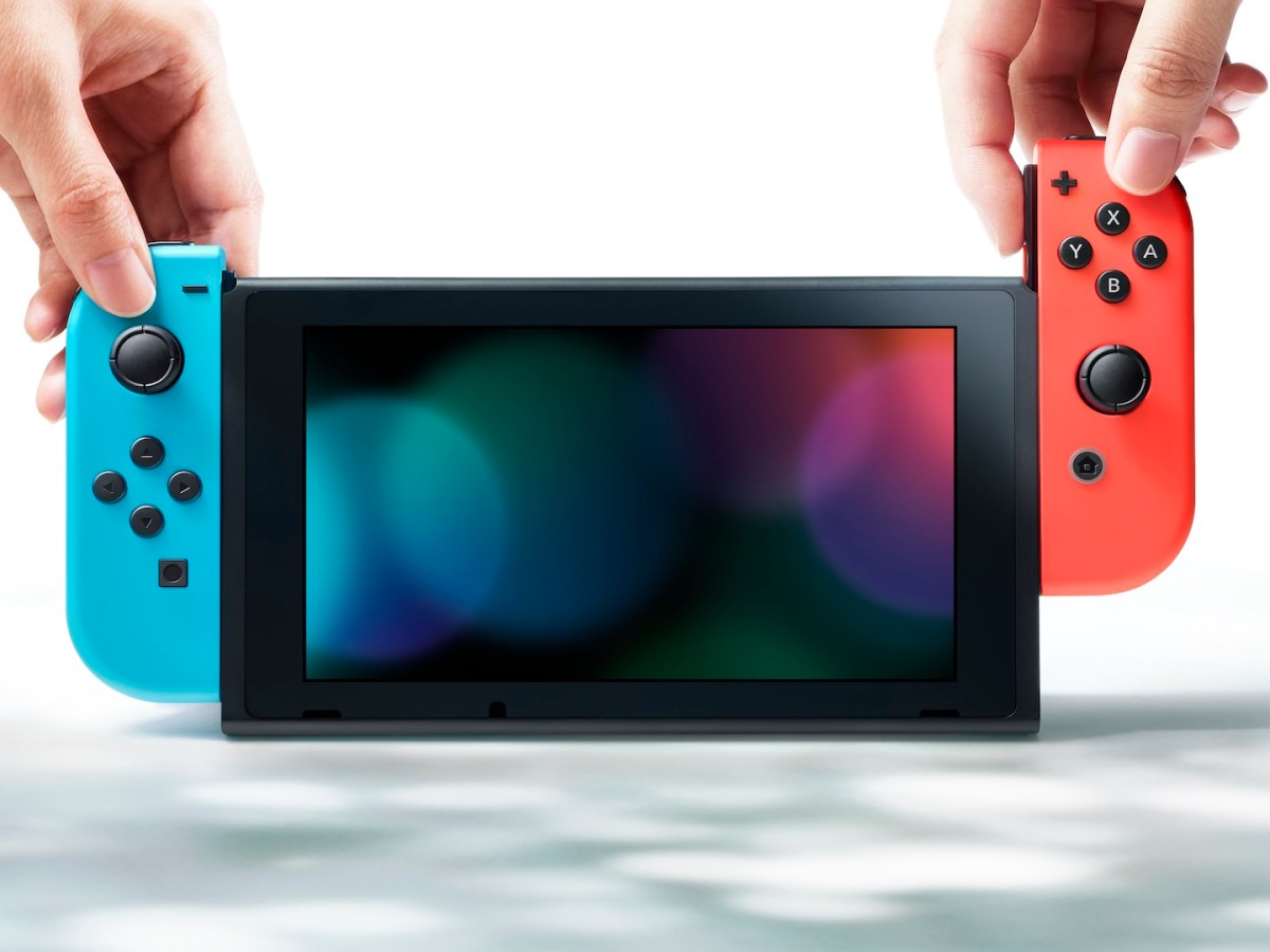 Eine Nintendo Switch mit rotem und blauen Joy-Con sowie zwei HÃ¤nden.